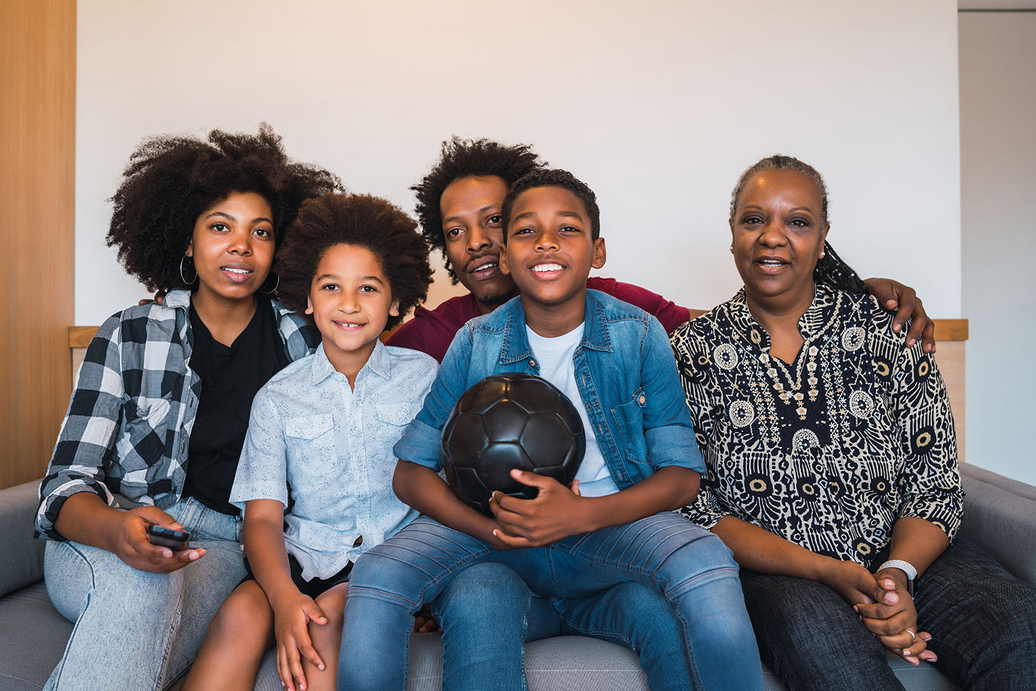 Multi-generation family watching soccer match at home. Happy african american multi-generation family watching soccer match on television in living room at home. Family and sport concept.